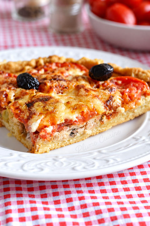 Part de tarte au thon et à la tomate avec des olives noires pour décorer.