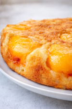 Gâteau aux pêches maison vu du dessus, doré et moelleux avec des demi‑pêches caramélisées sur le dessus.