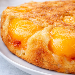 Gâteau aux pêches maison vu du dessus, doré et moelleux avec des demi‑pêches caramélisées sur le dessus.