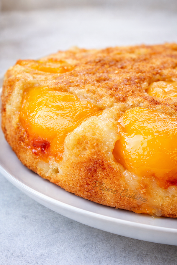Gâteau aux pêches maison vu du dessus, doré et moelleux avec des demi‑pêches caramélisées sur le dessus.