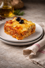 Part de lasagnes aubergines mozzarella présentée sur une assiette.