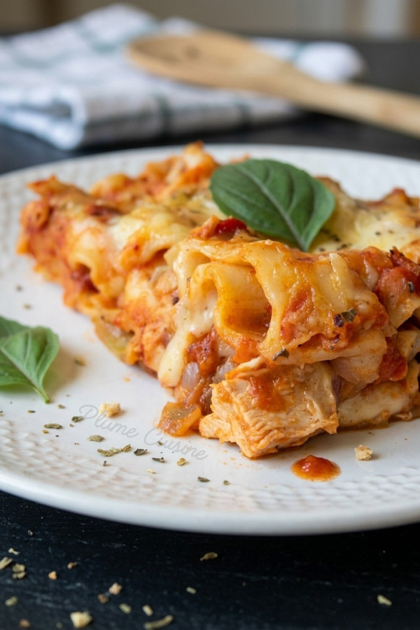 Portion généreuse de lasagnes au poulet fondantes, avec couches de pâtes, poulet tendre et sauce tomate crémeuse.