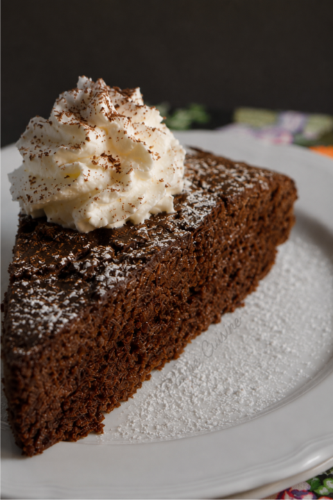 Gâteau au chocolat avec du chocolat en poudre servi sur une assiette blanche avec une généreuse chantilly