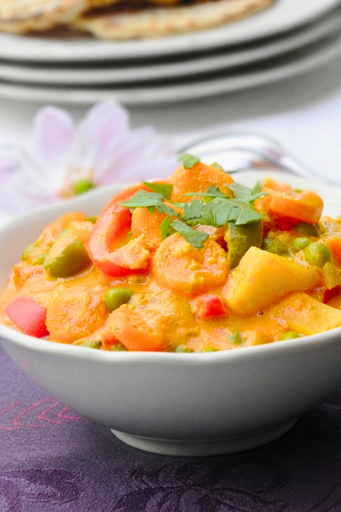 Korma végétarien crémeux aux légumes, servi dans un bol avec coriandre fraîche.