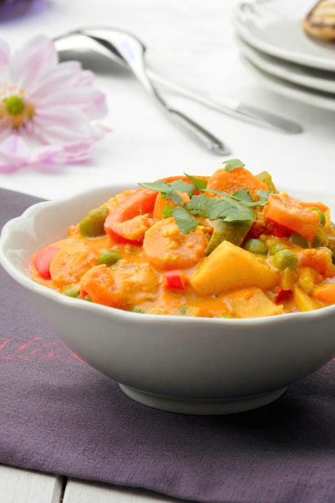 Bol de korma végétarien maison aux légumes colorés et sauce douce aux épices.