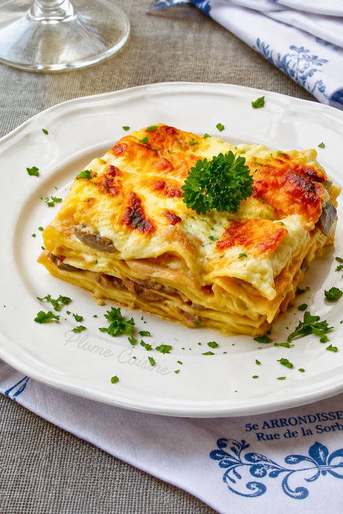 Lasagnes aux champignons crémeuses et gratinées, servies avec du persil frais dans une assiette blanche.