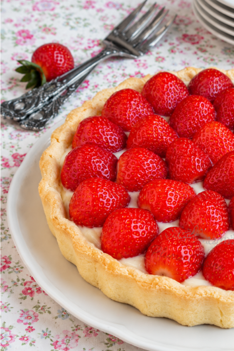 Tarte aux fraises maison garnie de crème pâtissière au coco onctueuse, avec une pâte sablée dorée et des fraises fraîches brillantes.