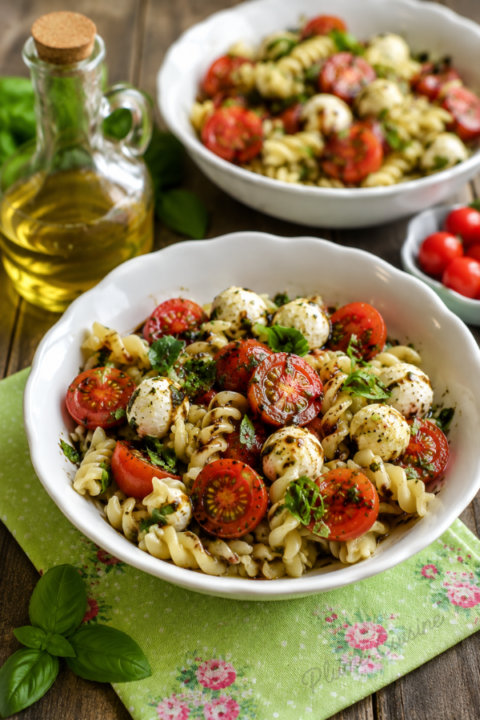 Deux bols de salade de pâtes tomates et mozzarella arrosés de vinaigrette