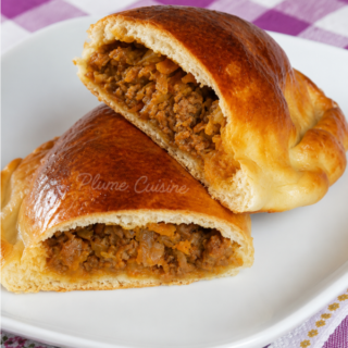 Délicieux pirogues à la viande coupées en deux sur une assiette blanche.
