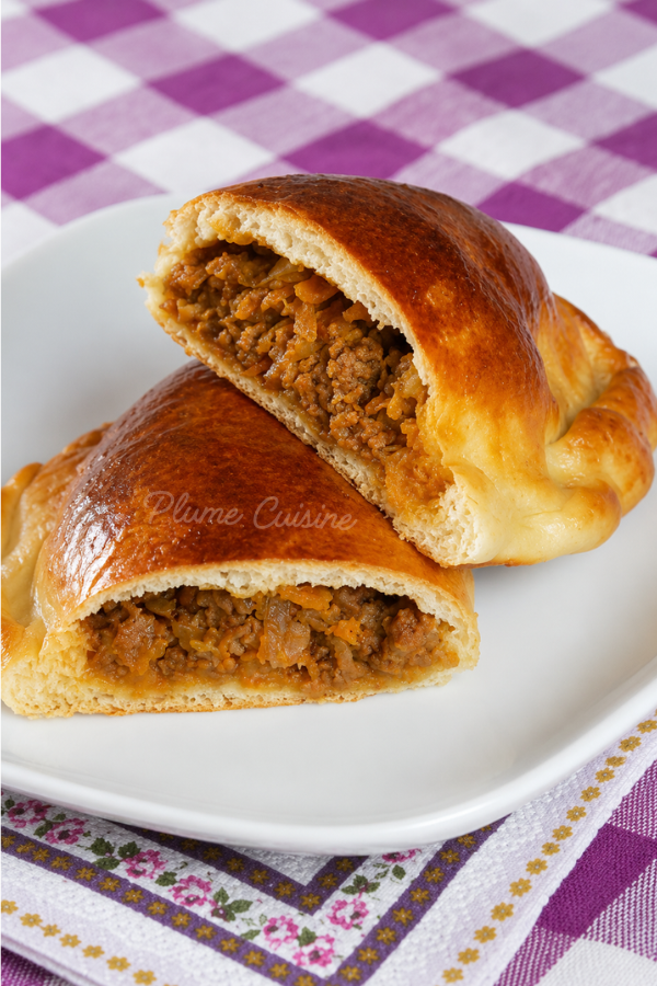 Délicieux pirogues à la viande coupées en deux sur une assiette blanche.