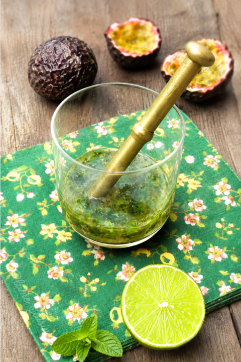 Feuilles de menthe, jus de citron et sucre écrasés dans un verre.