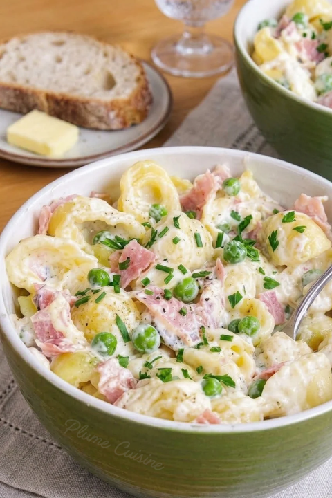 Gros plan d'un bol de pâtes crémeuses au jambon et petits pois