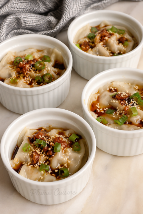 Quatre remequins blancs contenant des lasagnes de dumplings asiatiques
